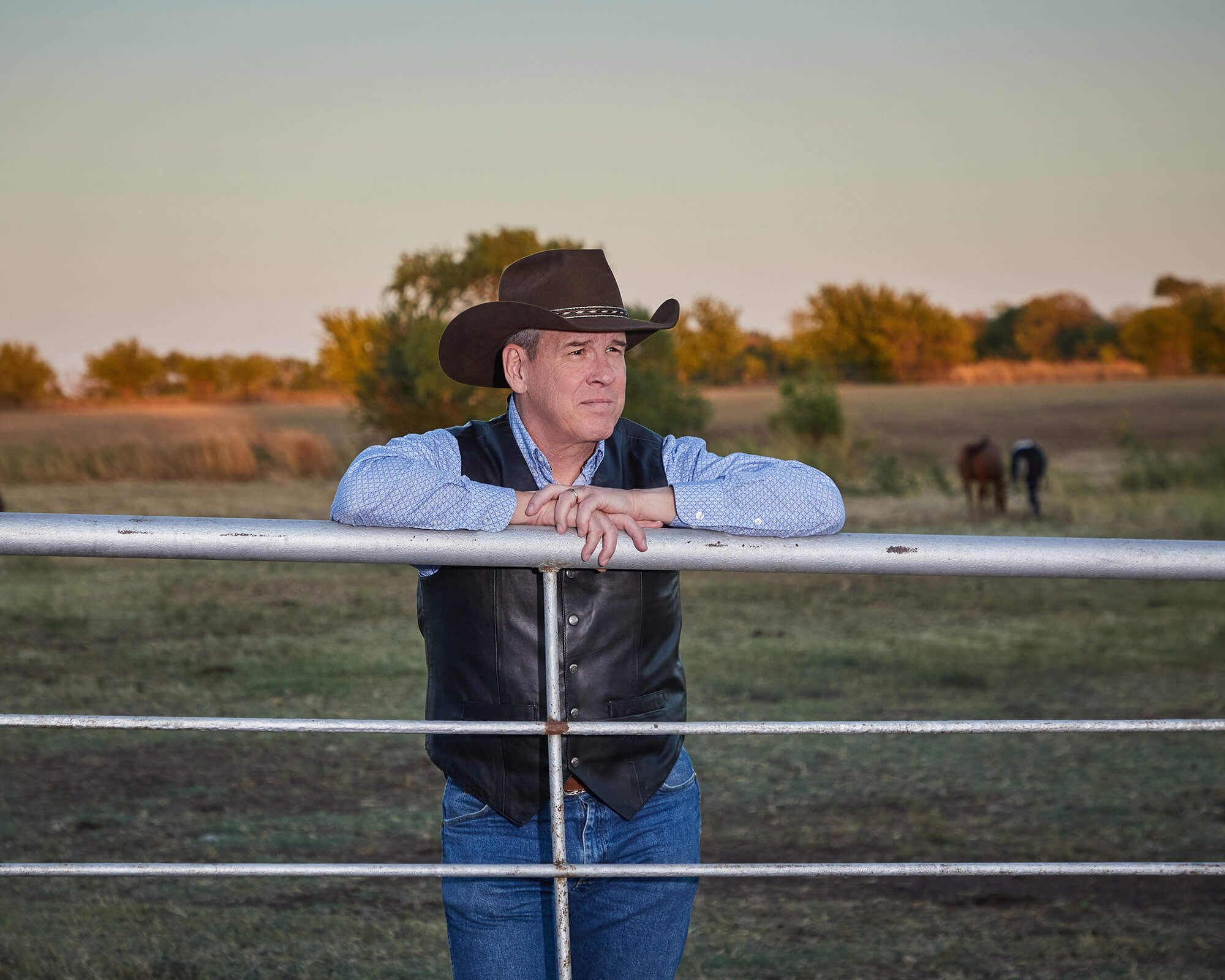Randy Cole in cowboy get up viewing the sunset from horse corral